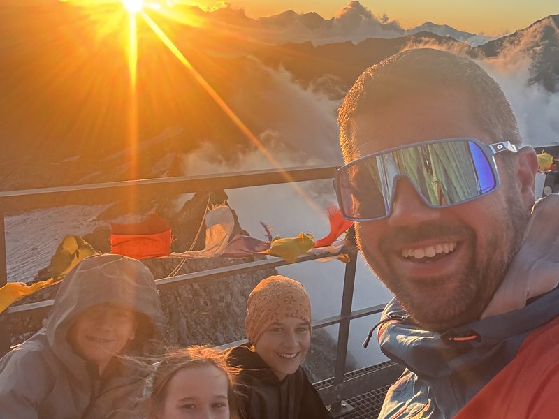 Rodina na horském vrcholu při západu slunce